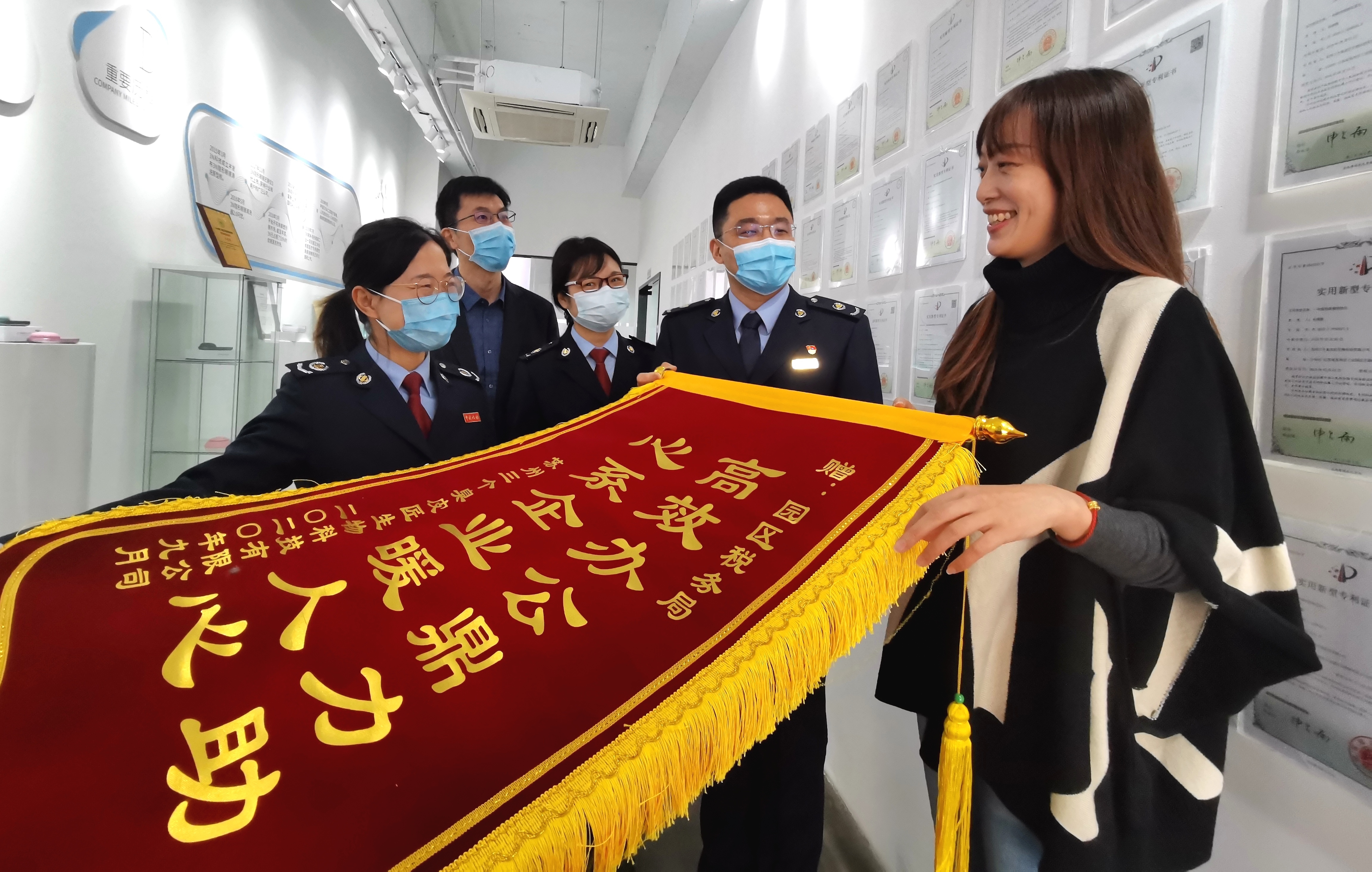 图为苏州3N生物科技有限公司副总经理白杨为前来走访的税务人员送锦旗。孙军/摄