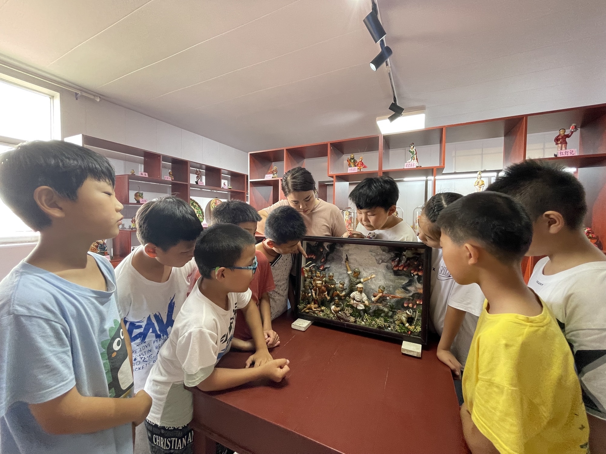 在社区非遗技艺展馆里，孩子们在巾帼志愿者带领下参观“塑”说党史主题展，了解面塑背后的红色故事