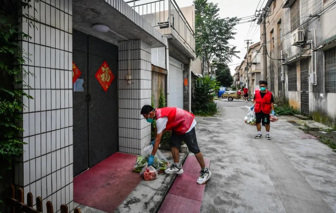 永兴社区志愿者在为臧家村居民发放蔬菜、肉等生活物资。南报融媒体记者 姚强 摄