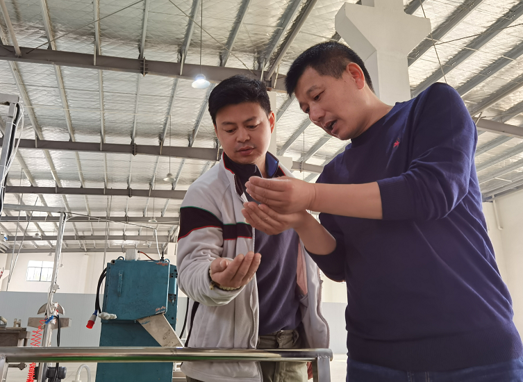 王华（右）正在和技术人员检查产品质量